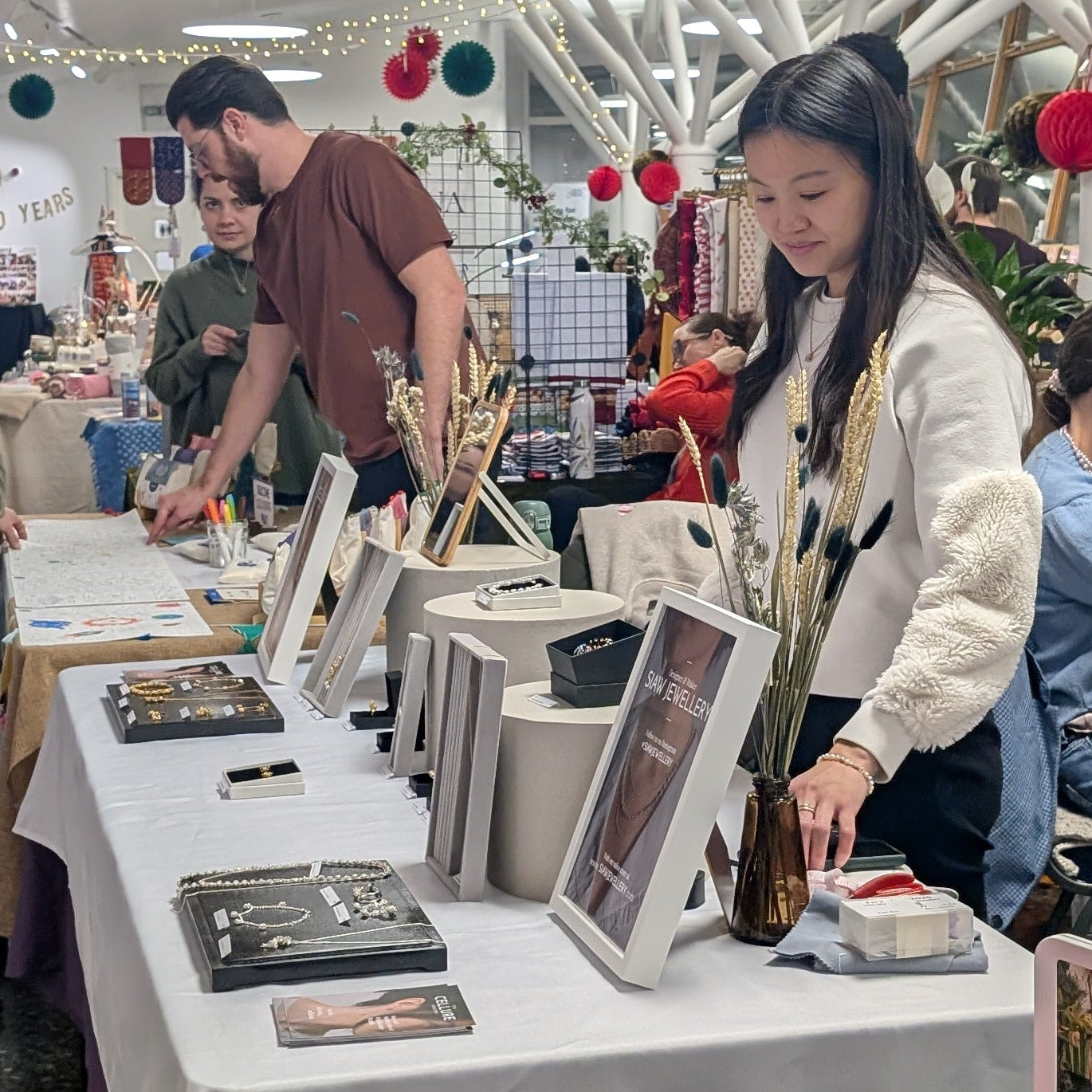 People shopping at a craft fair with tables displaying various items.